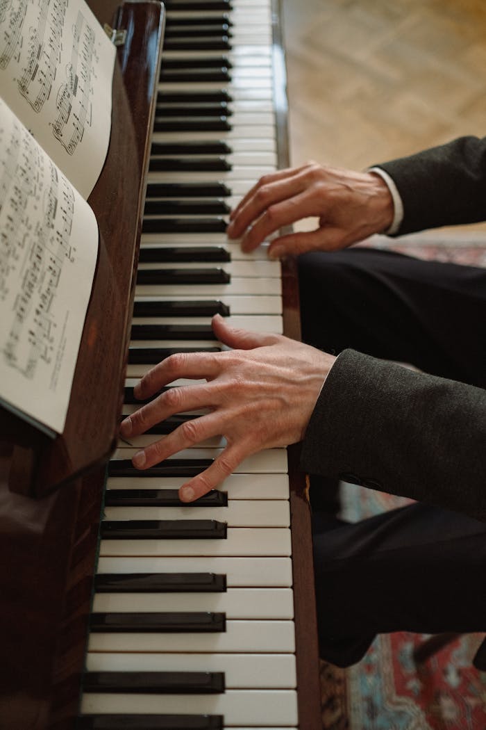 A detailed view of hands playing a piano with sheet music, showcasing musical artistry.