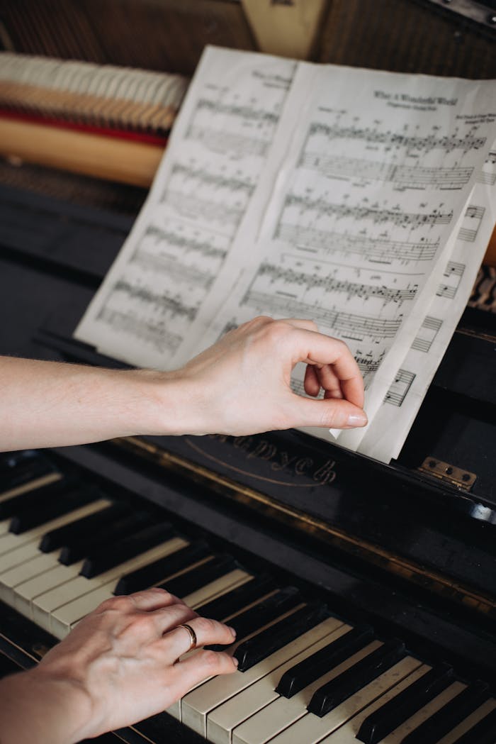 Woman's hands playing piano while turning sheet music, adding a personal touch.